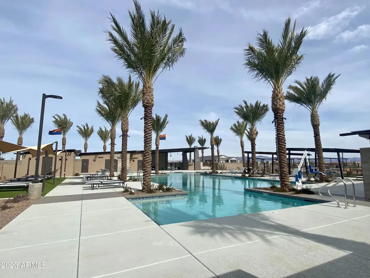 A tranquil community swimming pool surrounded by palm trees and lounge chairs, inviting residents to swim, sunbathe, or socialize. The atmosphere is relaxing, evoking a resort-like community experience.