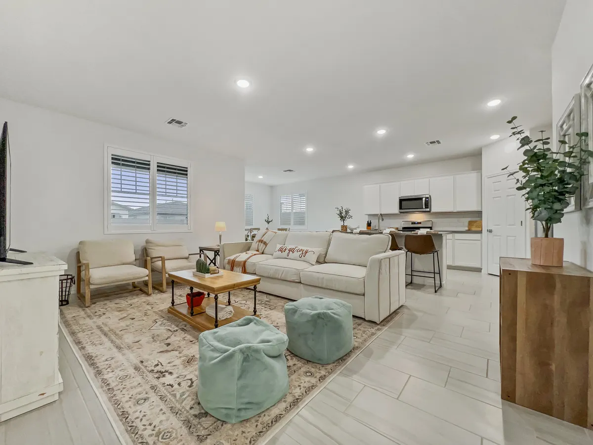 An open-plan living area with a comfortable sofa, coffee table, and television, accented by decorative plants. The space is well-suited for socializing, game nights, or movie marathons—central to the indoor group gathering experience.