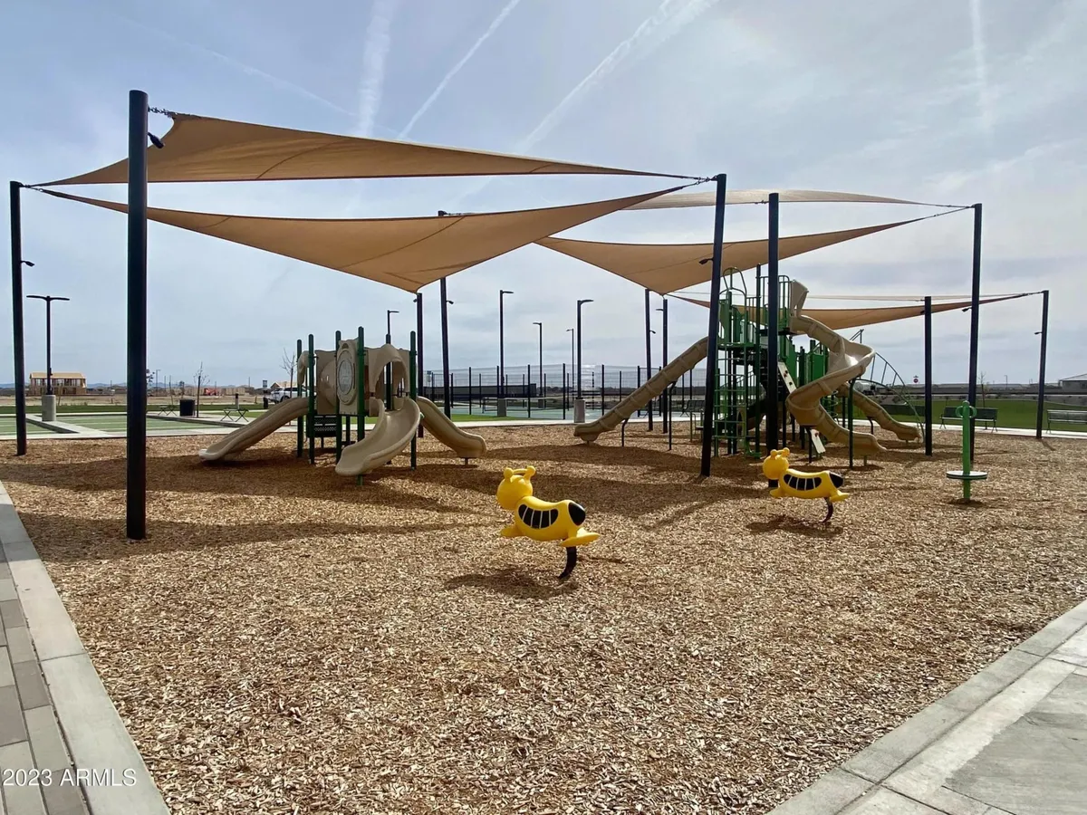 An exterior shot of a vibrant playground equipped with colorful spring riders and shade sails. The area is designed for children’s play, with ample space for families to gather, and provides a joyful, energetic atmosphere that speaks to the playful spirit of the section.